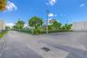 Asphalt parking area featuring perimeter chain-link fencing, stadium-style lighting poles, and mature landscaping