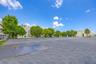 Expansive asphalt parking area featuring marked parking stalls, perimeter chain-link fencing, and mature landscaping