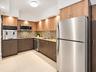 Kitchen featuring two-tone flat-panel cabinetry, stone-finish countertops, multi-tonal glass tile backsplash, stainless steel appliances, and large-fo