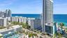 High-rise architectural structure with floor-to-ceiling glass windows, integrated rooftop pool, and coastal shoreline exposure