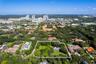 Aerial perspective of a sprawling lot featuring mature tree canopy, open green space, and a low-profile residential structure