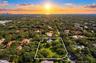Aerial perspective of a sprawling parcel featuring expansive green lawns, established mature trees, and a distant horizon backdrop