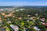 Aerial view of a sprawling lot featuring mature trees, expansive green space, and a backdrop of the urban skyline