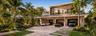Modern exterior featuring a three-car garage, floor-to-ceiling glass windows, a glass-panel balcony railing, and natural stone paver driveway with int