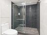 Walk-in shower featuring a sliding glass door, high-contrast black mosaic tile surround, built-in recessed shelving, stainless steel rainfall shower h