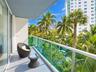 Private balcony featuring a glass panel railing and expansive tropical landscaping