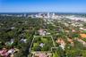 Aerial perspective featuring an expansive lot with mature canopy trees, a private swimming pool, and a skyline backdrop