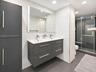 Floating double vanity with a quartz countertop, rectangular vessel sinks, floor-to-ceiling large-format tile wall cladding, and a glass-enclosed show