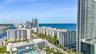 High-rise cityscape featuring multi-story residential structures, coastal proximity, prominent ocean water, and established palm tree landscaping