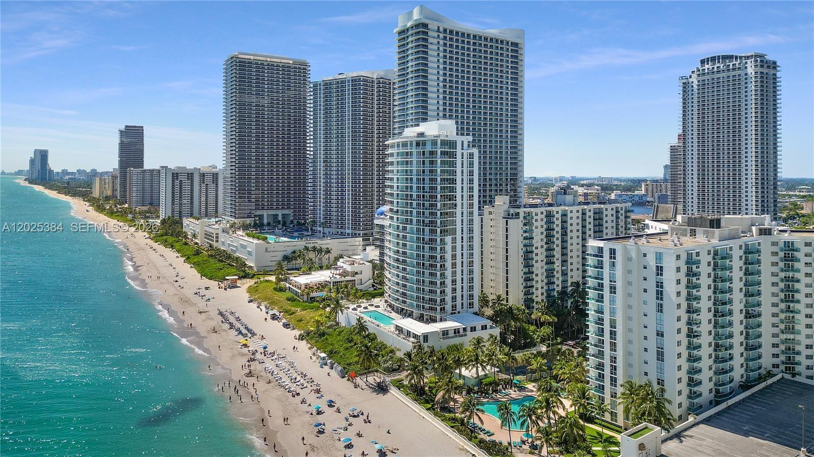 Aerial coastal perspective featuring direct beach access, high-rise residential architecture, and ground-level outdoor swimming pools