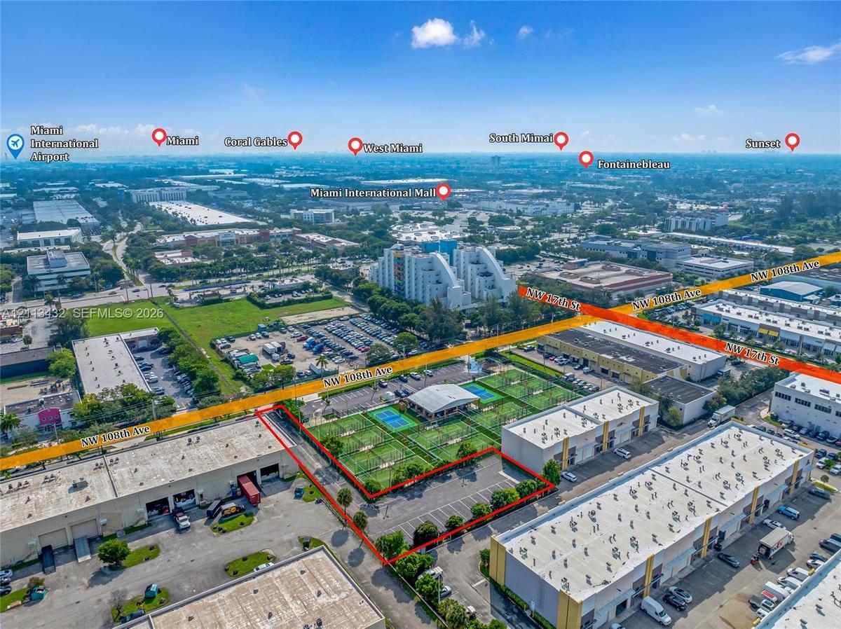 Aerial perspective of a commercial property featuring a private surface parking lot, paved exterior grounds, and proximity to major regional thoroughf