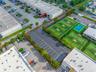 Asphalt-paved parking area featuring striped individual spaces, mature perimeter landscaping, and fenced boundaries