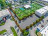 Asphalt-paved surface parking lot featuring designated stall markings, perimeter landscaping with mature trees.