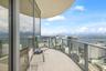 Curved private balcony featuring floor-to-ceiling glass wall, light-toned stone tile flooring, and a metal railing
