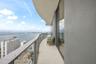 Curved wrap-around balcony featuring a glass panel railing, tile flooring, and floor-to-ceiling glass wall
