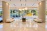 Grand lobby featuring polished stone flooring, expansive floor-to-ceiling glass paneling, dual curved structural columns, and contemporary suspended m