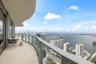 Curved balcony featuring a concrete floor, glass panel railing, and expansive water and skyline scenery