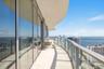 Expansive curved balcony featuring floor-to-ceiling glass paneling, tile flooring, and a sleek metal railing