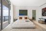 Floor-to-ceiling glass sliding doors, private balcony with metal railing, textured patterned wall treatment, and smooth-finish flooring