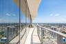 Curved exterior balcony featuring full-height glass curtain walls, concrete flooring, and a sleek metal railing