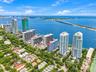 Aerial perspective showcasing high-rise residential architecture, coastal proximity, waterfront orientation, and expansive canopy coverage