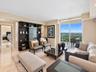 Living area featuring polished stone flooring, custom dark-finished built-in shelving, floor-to-ceiling glass sliding doors, and a private balcony