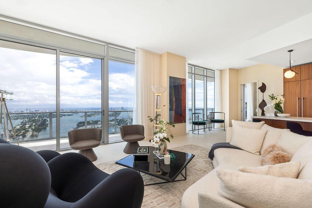 Floor-to-ceiling glass windows, expansive private balcony with glass railing, open-concept living area, custom flat-panel wood cabinetry, and neutral 