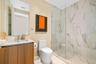 Bathroom featuring a wood-finish vanity with a stone countertop, wall-to-wall mirror, glass-enclosed walk-in shower with floor-to-ceiling stone-style 