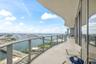 Expansive covered balcony featuring glass panel railings, concrete flooring, and full-height exterior windows