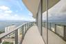 Curved balcony featuring light-colored tile flooring, a glass panel railing, and full-height floor-to-ceiling windows
