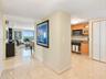 Polished stone flooring throughout, kitchen featuring wood-finish cabinetry, stone countertops, stainless steel appliances, and built-in closet storag