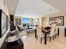 Open-concept living and dining area featuring polished stone tile flooring, recessed ceiling lighting, a dedicated multi-pendant light fixture, and fl