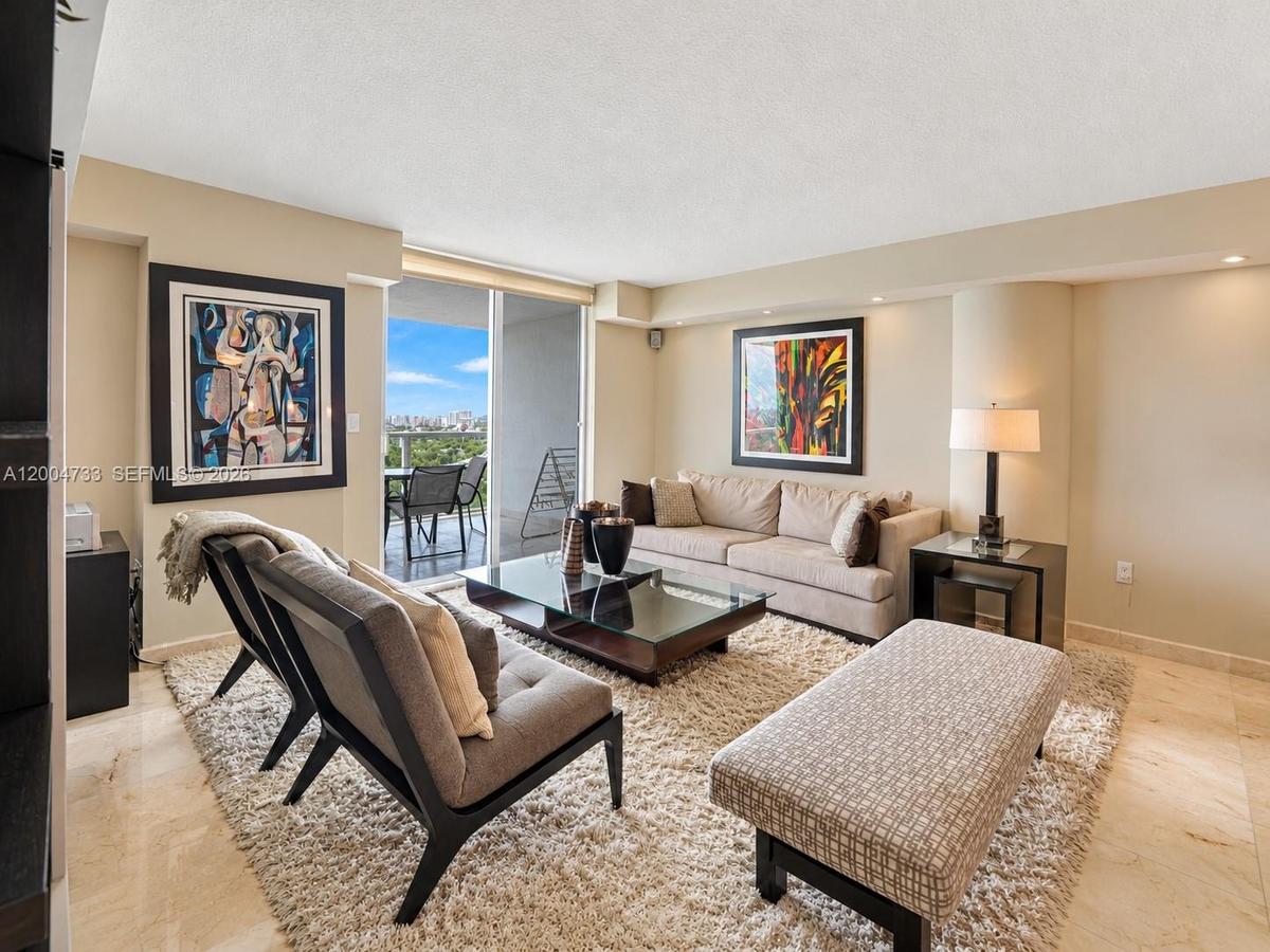 Living area featuring stone flooring, recessed ceiling lighting, and a sliding glass door providing access to a private balcony