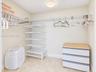 Walk-in closet featuring white wire shelving, wall-mounted adjustable rack system, and stone-finish tile flooring