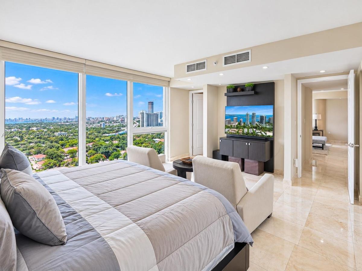 Floor-to-ceiling windows featuring panoramic city and water scenery, polished stone flooring, and built-in dark cabinetry with recessed lighting