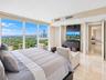 Floor-to-ceiling windows featuring panoramic city and water scenery, polished stone flooring, and built-in dark cabinetry with recessed lighting