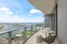 Covered wrap-around balcony featuring glass panel railings, neutral stone-finish flooring, and floor-to-ceiling glass windows