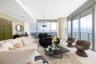 Floor-to-ceiling glass walls, sleek cylindrical architectural column, recessed linear lighting, polished neutral flooring, and integrated balcony acce