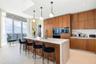 Kitchen featuring flat-panel wood cabinetry, stone-finish waterfall island with an undermount sink, built-in stainless steel appliances, and spherical