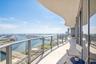 Curved balcony featuring a glass railing system, concrete flooring, and an overhanging structural soffit