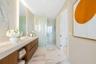 Floating wood-finish vanity with countertop, integrated wall-to-ceiling mirror, stone-finish tile flooring, and glass-enclosed shower