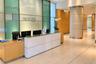 Reception area featuring stone-finish flooring, wood-paneled walls, a built-in stone-top reception desk, and a prominent cylindrical structural column