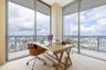 Floor-to-ceiling windows, wrap-around glazing, light-toned tile flooring, and a glass-enclosed balcony