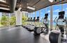 Fitness center featuring floor-to-ceiling windows, industrial-style exposed ceiling, and resilient rubberized flooring