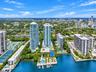 Aerial perspective featuring waterfront high-rise towers, a private marina, multiple swimming pools, and dedicated tennis courts