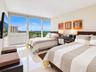 Floor-to-ceiling windows featuring expansive urban and nature scenery, neutral polished tile flooring, and a wall-mounted television console