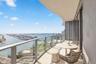 Covered balcony with a curved ceiling, glass panel railing, and expansive water and urban surroundings