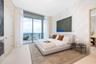 Floor-to-ceiling glass sliding doors opening to a private balcony, textured wall paneling, and stone flooring
