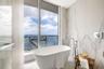 Freestanding soaking tub with polished chrome floor-mounted faucet, floor-to-ceiling porcelain wall tile, expansive window wall, and integrated balcon