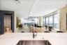 Kitchen featuring a stone-surface island, stainless steel undermount sink, and chrome high-arc faucet